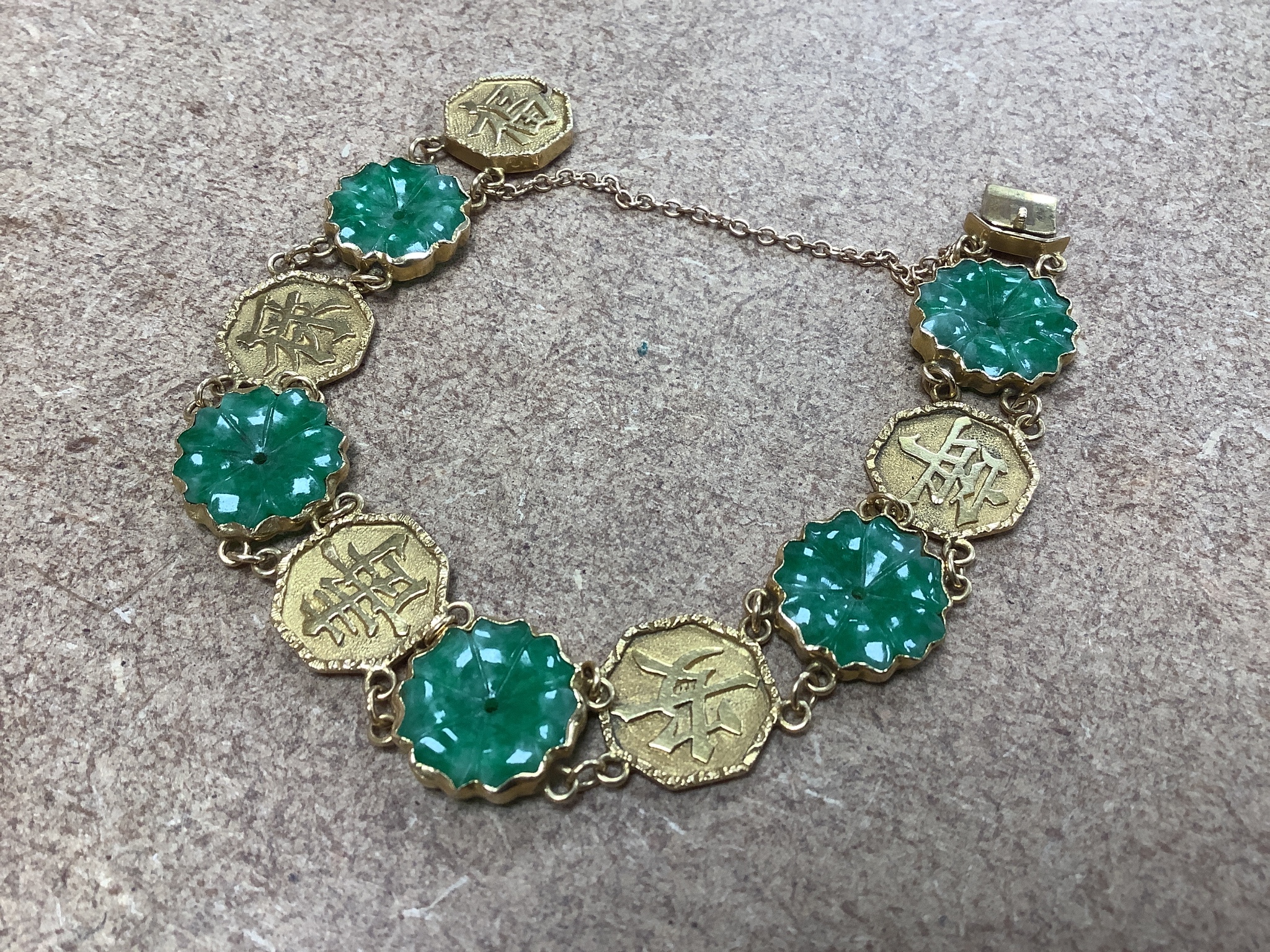 A Chinese yellow metal (stamped WH 20) and carved jadeite disc set bracelet, 18cm, gross 19 grams.